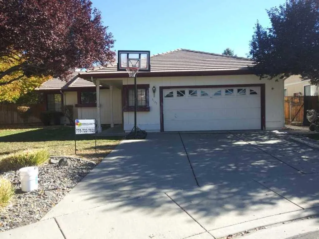 Tan stucco house with white garage doors after repaint
